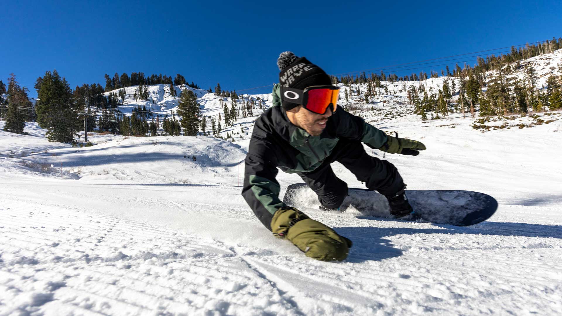 Snowboarder in dark jacket leaning into turn on groomed slope