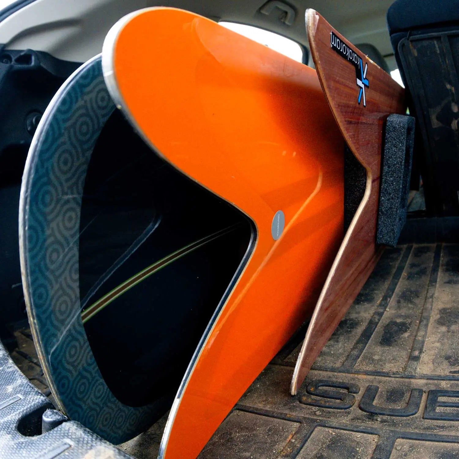 Orange kayak and wooden fin loaded in car trunk