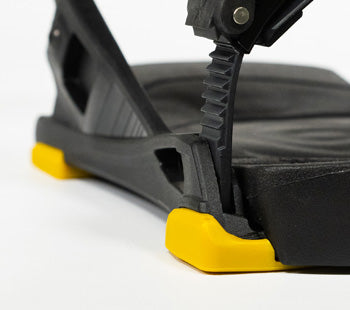 Close-up of black snowboard binding with yellow rubber corner bumpers