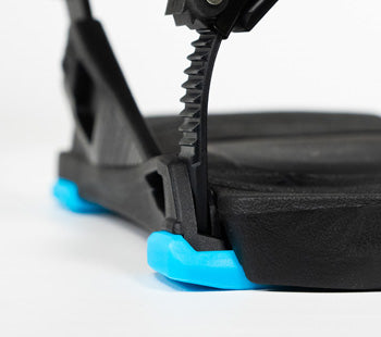 Close-up of black snowboard binding with blue rubber bumpers, ratchet strap