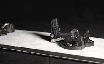 Black ski touring binding mounted on white ski, close-up angle