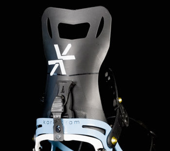 Black snowboard binding highback with white logo, close-up view