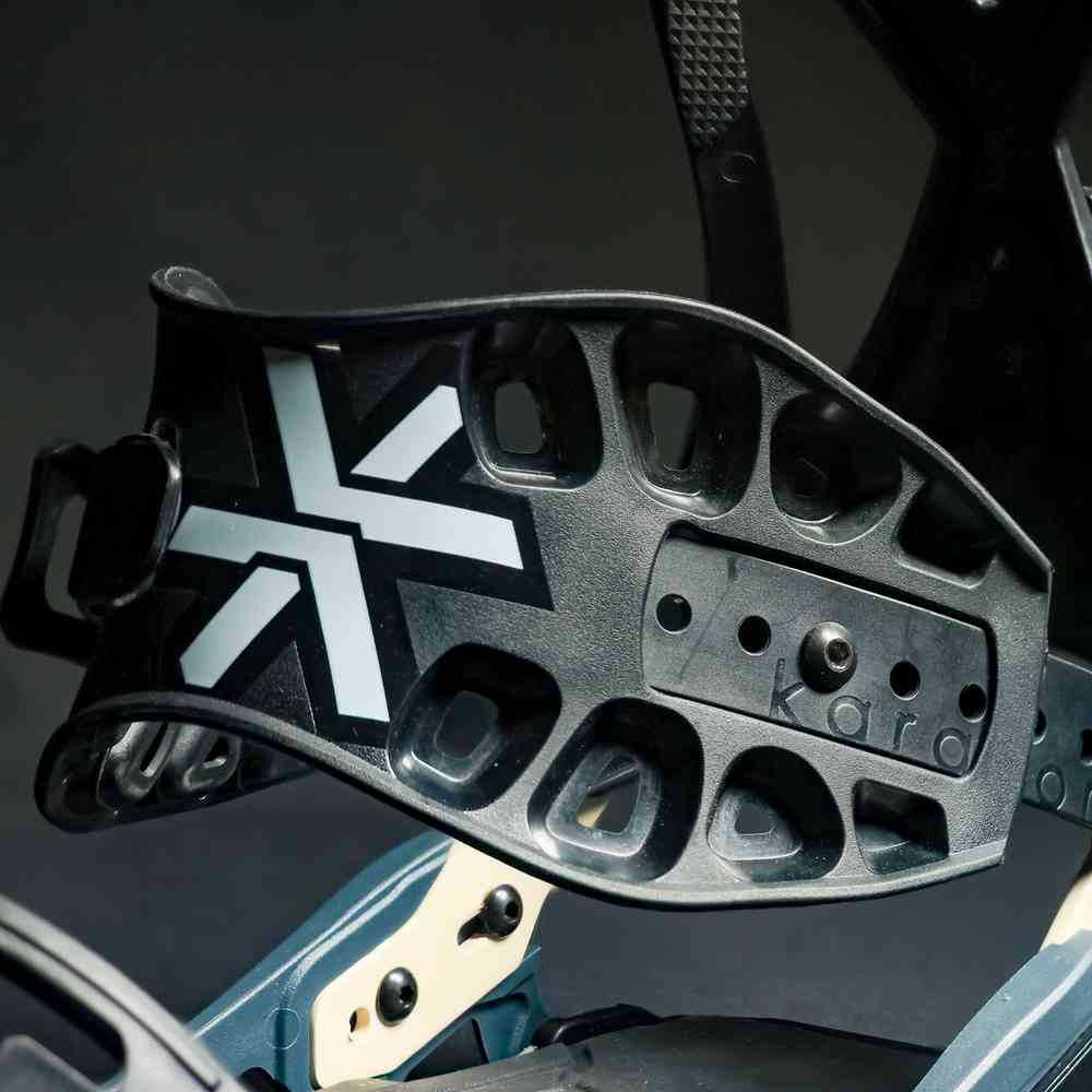 Close-up of black snowboard binding highback with perforated holes and logo