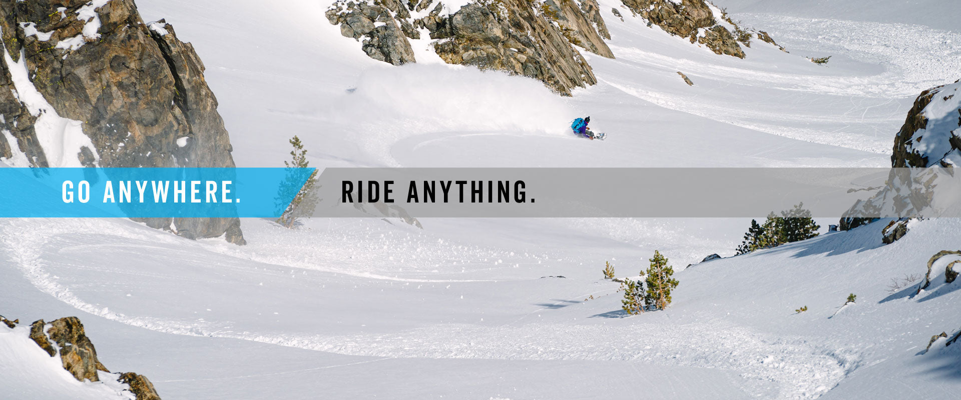 Snowboarder carving deep powder between rocky cliffs on snowy mountain