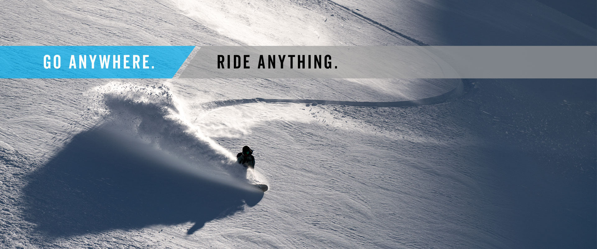 Snowboarder carving through deep powder, spraying snow on mountain slope
