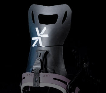 Black snowboard binding highback with white logo, close-up angle