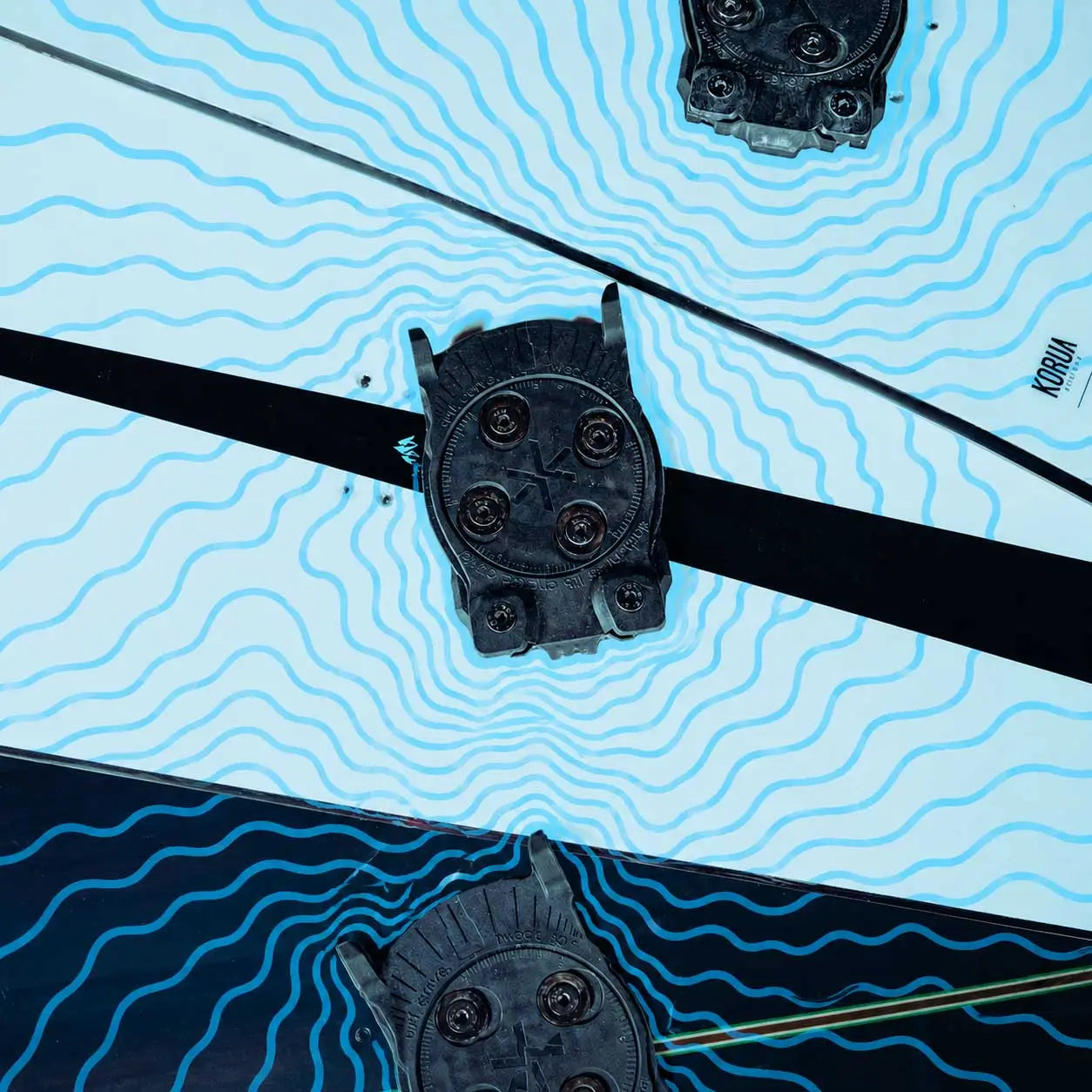 Snowboard binding discs on wavy blue line pattern, close-up