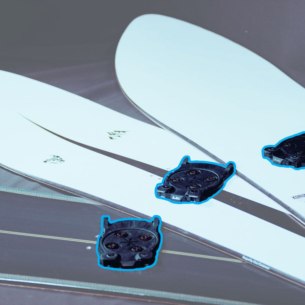 Black touring binding inserts mounted on white ski tips, top view