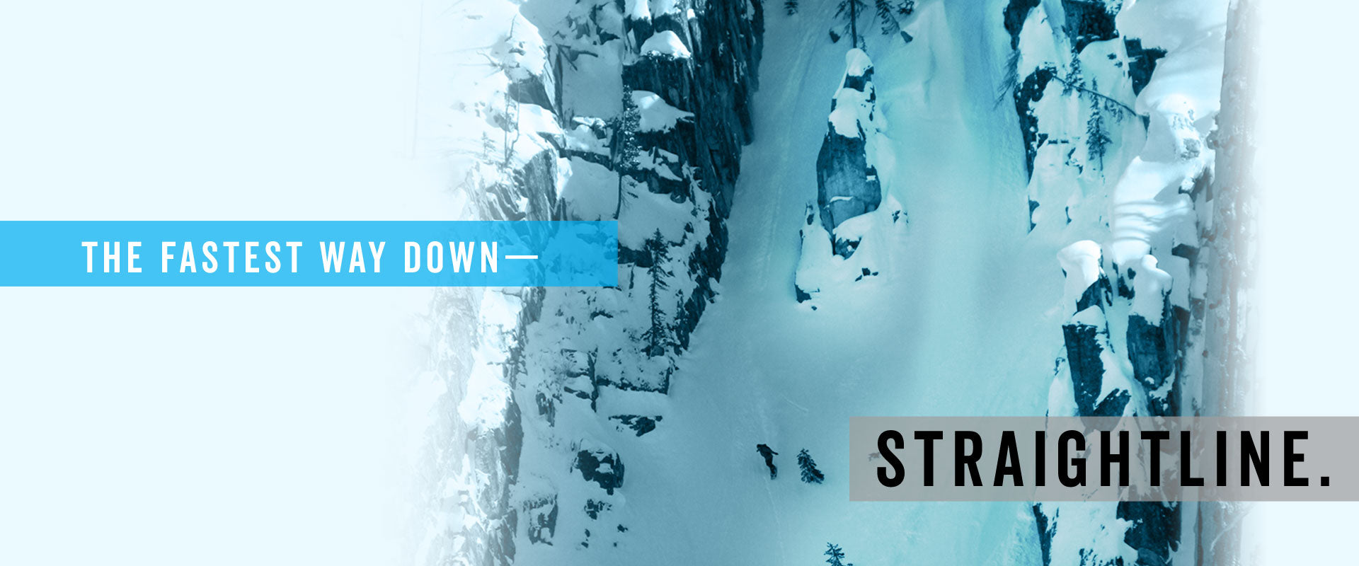 Skier descending narrow snowy couloir between rocky cliffs, aerial view