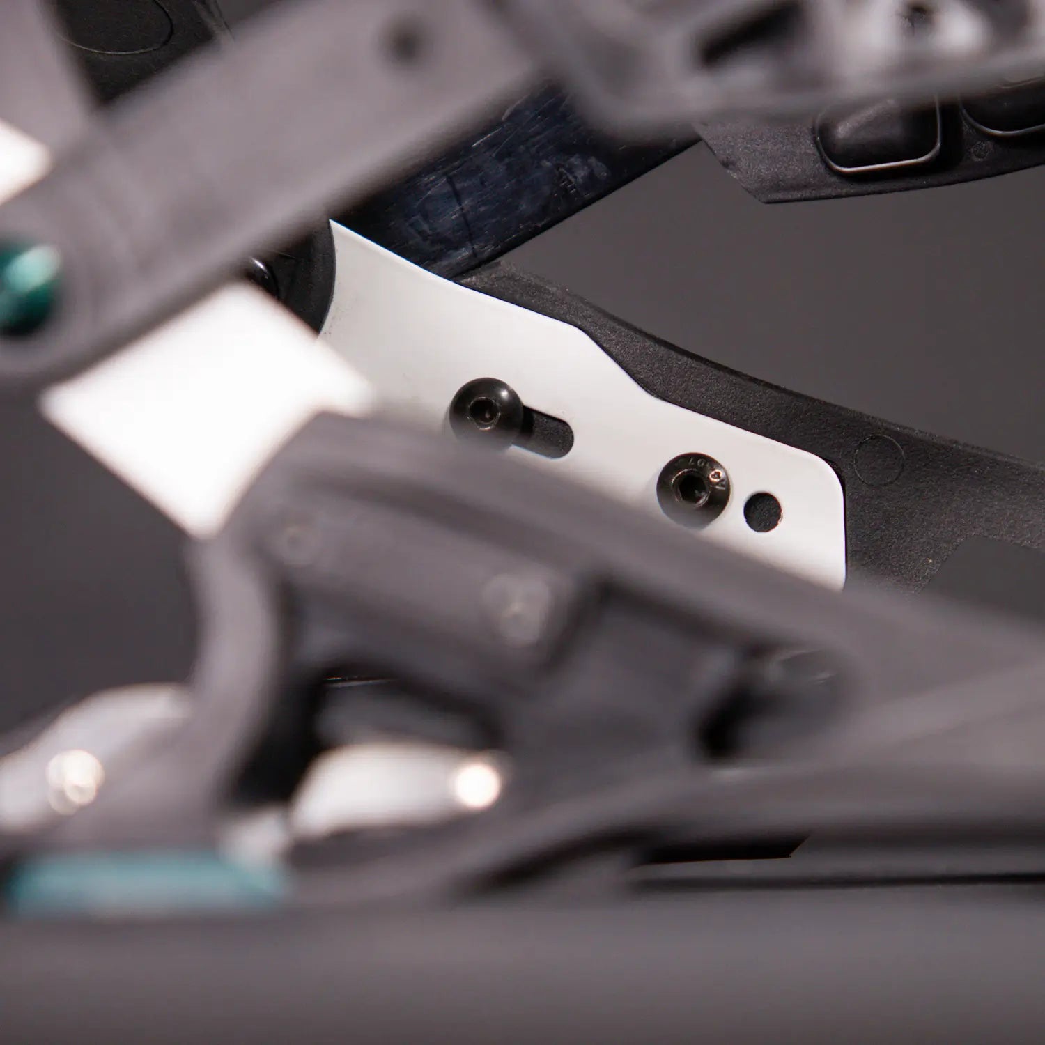 Close-up of black snowboard binding mechanism with white mounting plate screws