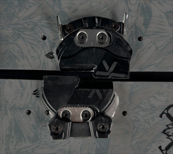 Black snowboard binding mounted on patterned gray board, top view